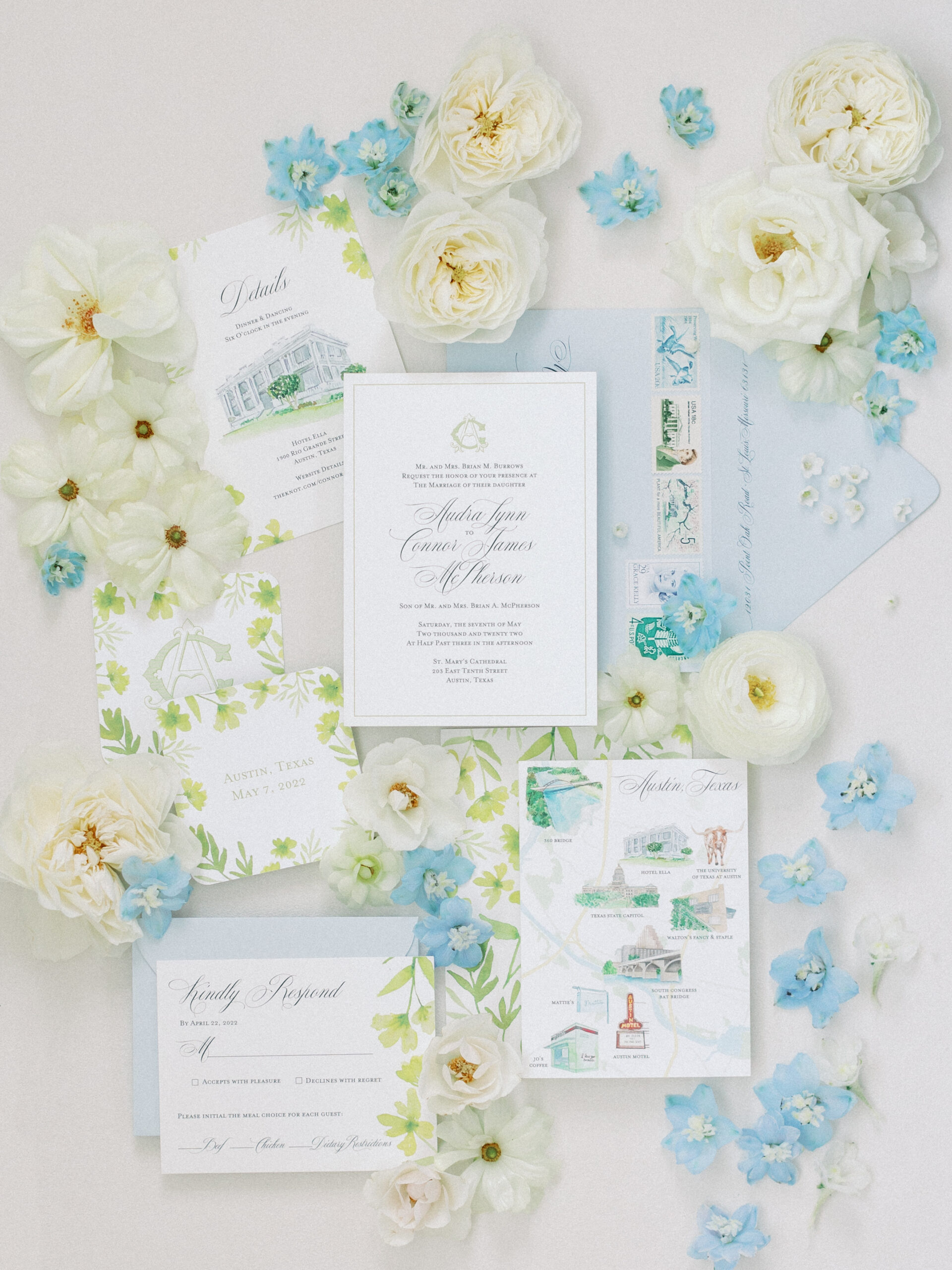 hotel ella invitation suite for wedding styled on a board with flowers around blue and white